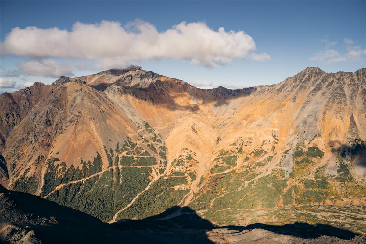 A mountain range with trees and clouds  AI-generated content may be incorrect.